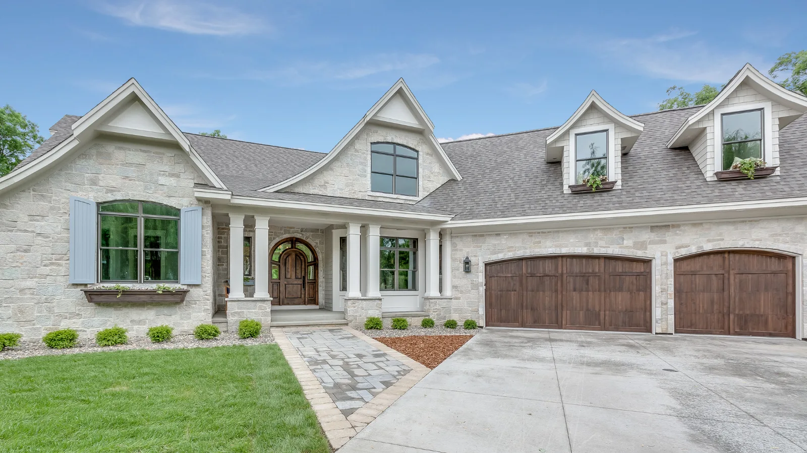Light stone house with a gray shingle roof and an attached garage